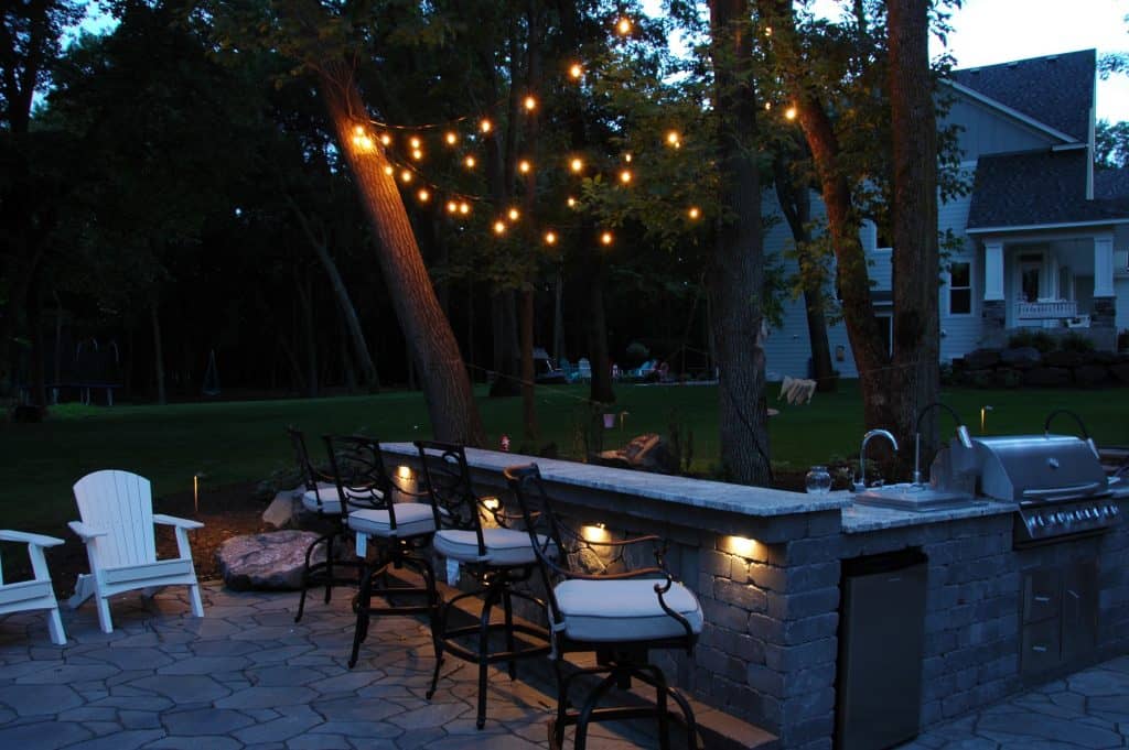 An outdoor kitchen with landscape lighting and The Bistro Package.