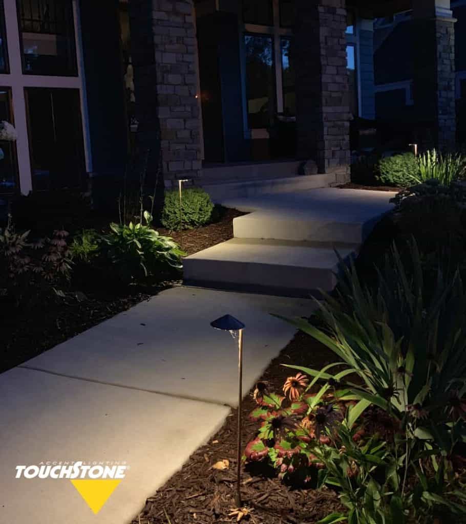 A home with The Gardener Package illuminating the walkway and highlighting the plants at night.