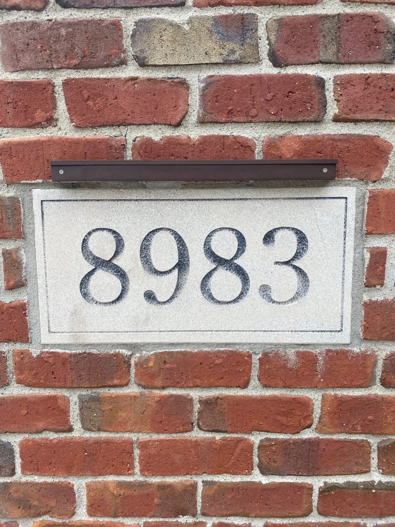 IMG_0835 A rectangular plaque from the Ledge Bar Series with the number 8983 is mounted on a red brick wall.