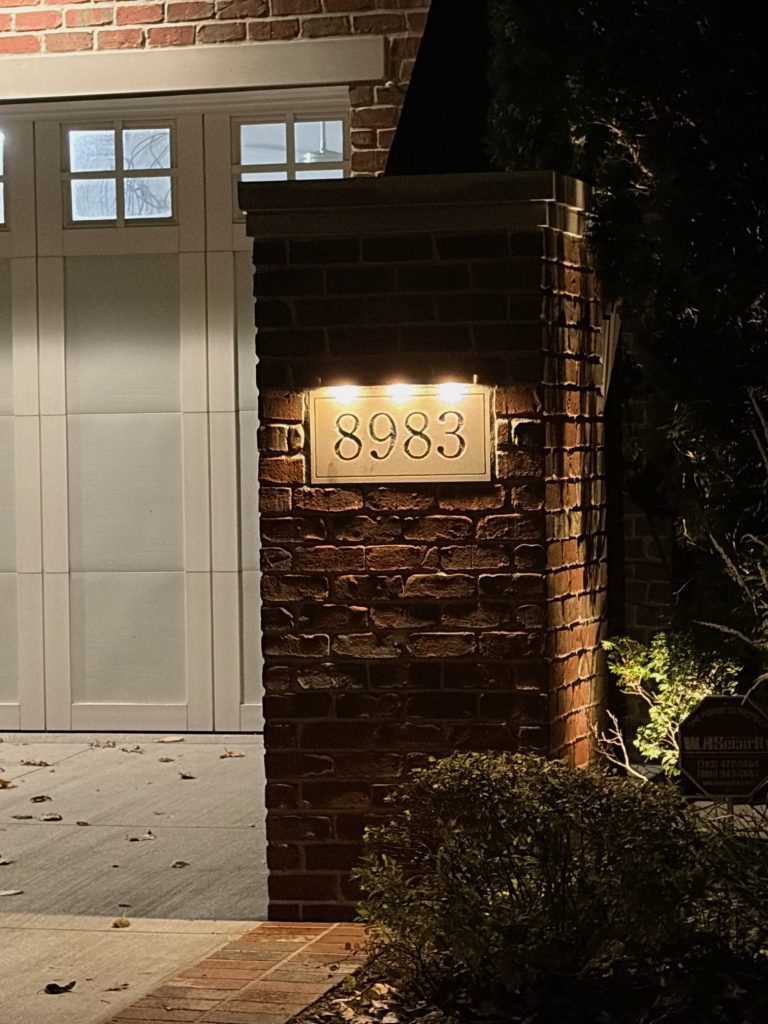 IMG_2615 A brick pillar featuring the house number 8983, illuminated by two Ledge Bar Series lights, stands in front of a garage at night.